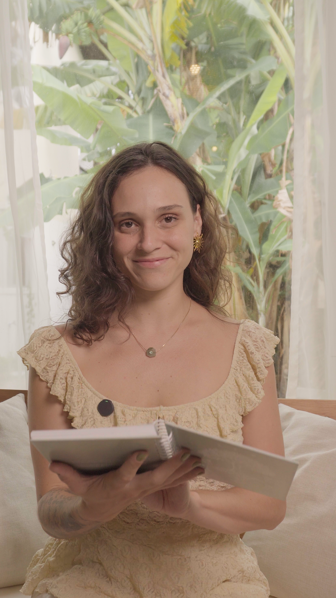 Mariana Tevah em ambiente natural, apoiada sobre uma mesa com notebook